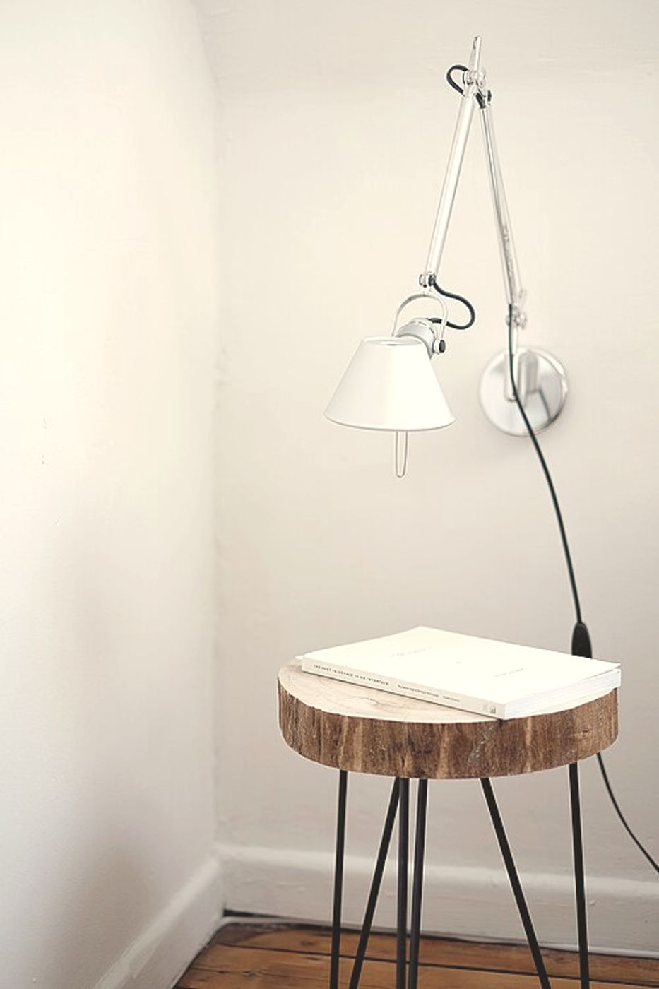 Een houten bijzettafel met boek tegen een lichte wand